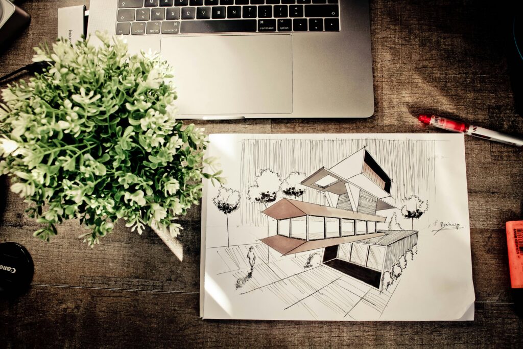 A detailed architectural design sketch on an office desk with a laptop and plant, fostering creativity.